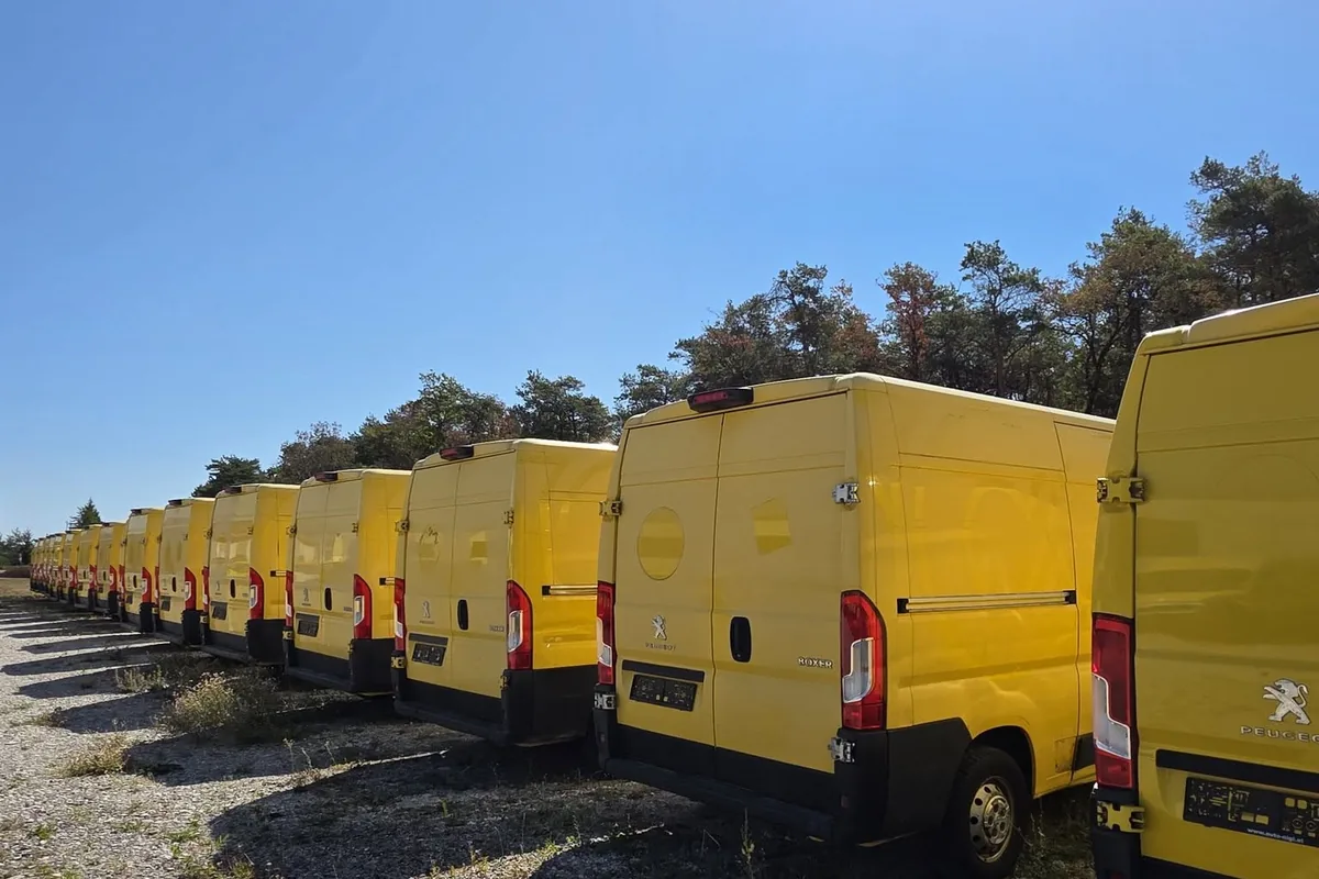 Lange Reihe gelber Kastenwagen von hinten auf dem Schotterplatz